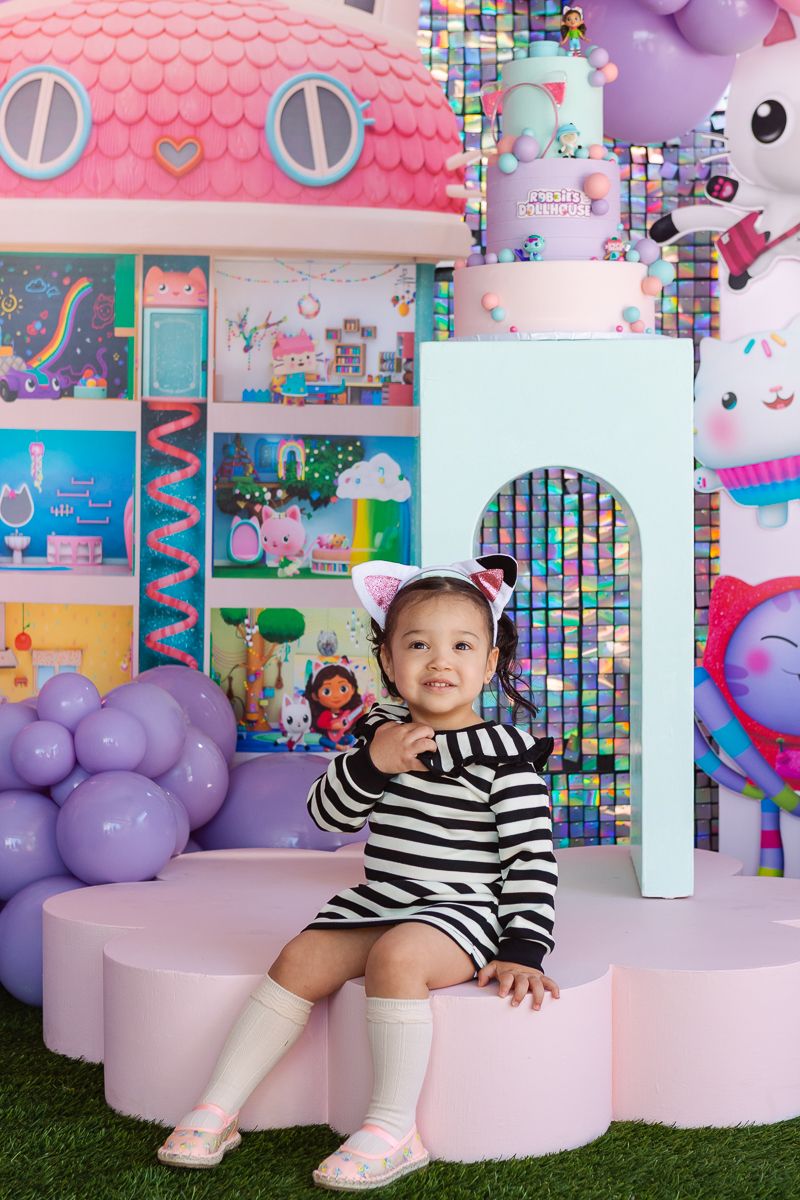 Candid joy—birthday girl posing with the pastel-themed Gaby’s Dollhouse decor at her NYC celebration