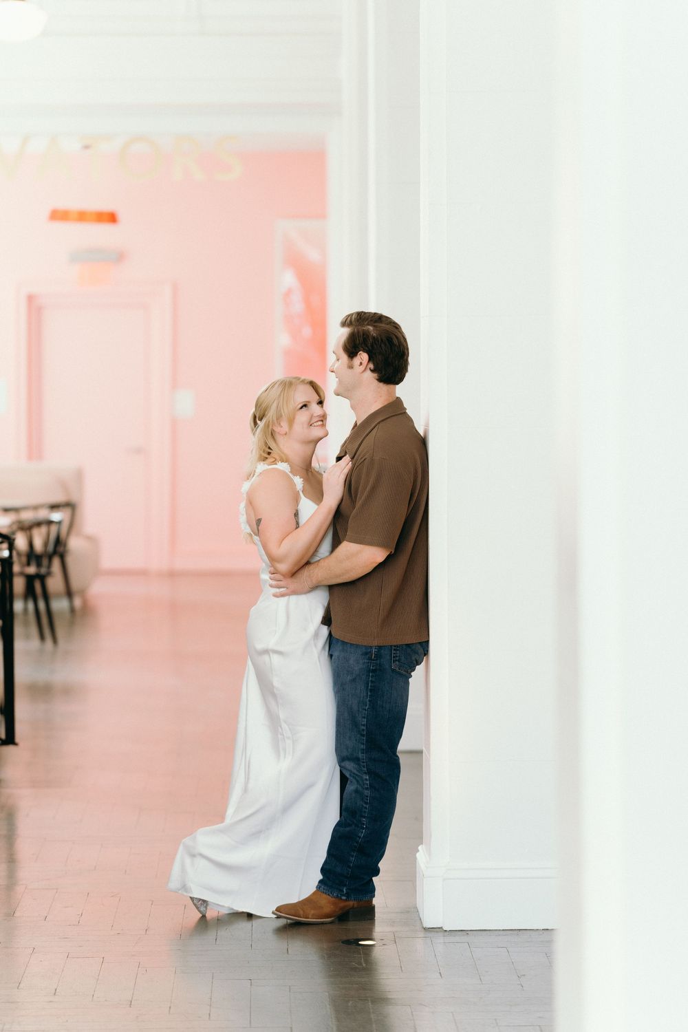 A couple shares an intimate dance in a room with pink walls and classic architectural details.