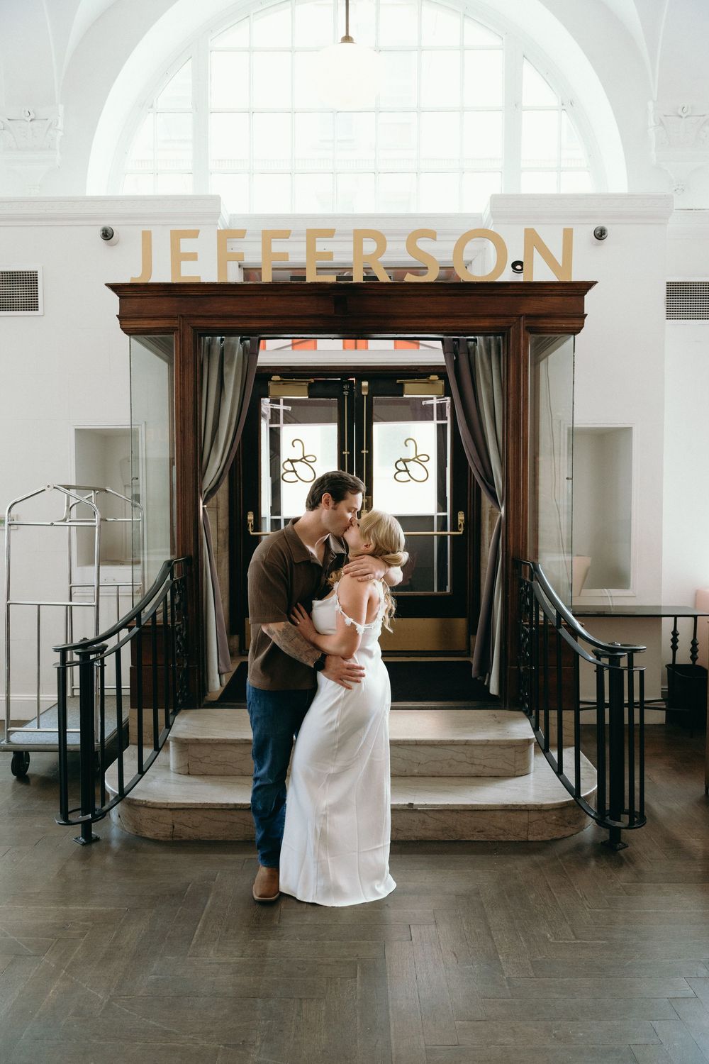 Interior wedding photo at Jefferson entrance with arched window and wooden doorway.