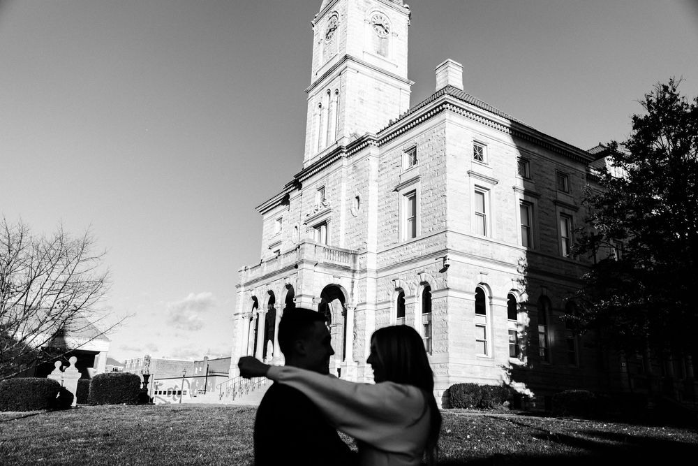 A dramatic black and white view of a historic building with a clock tower from a low angle perspective.