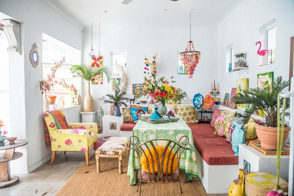 Bright and colorful sunroom decorated with tropical plants, floral prints, and eclectic vintage furniture.