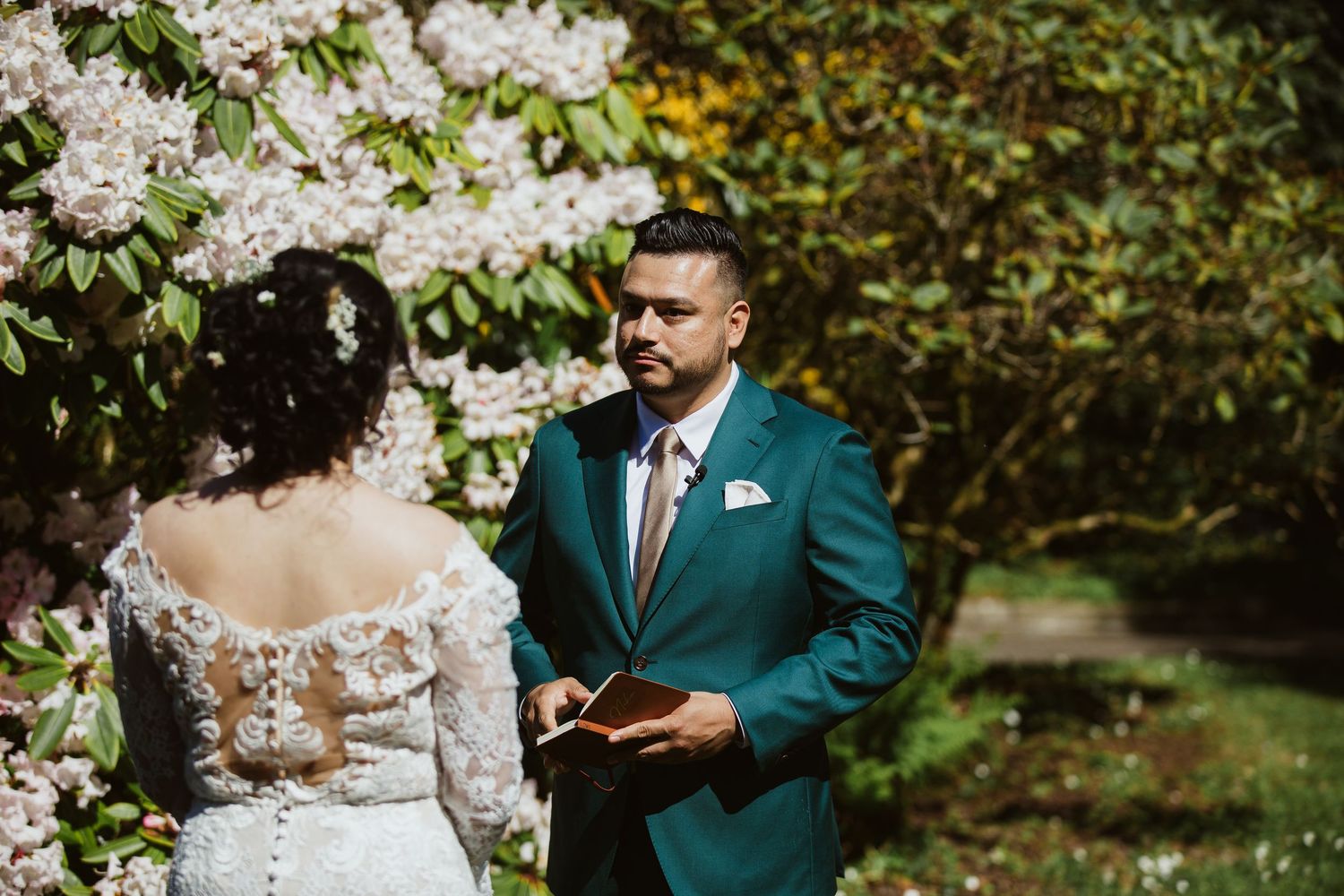 A couple shares an intimate moment surrounded by blooming white spring flowers in a garden setting.