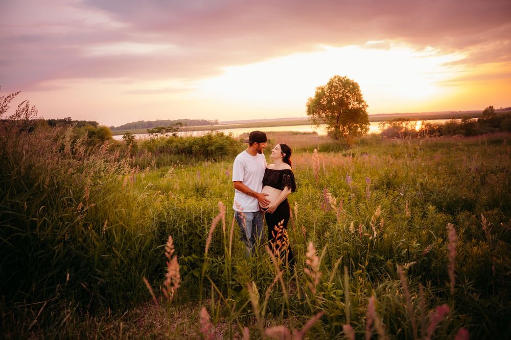 Silhouetted couple embraces in sun-drenched golden meadow at sunset during romantic outdoor photoshoot.