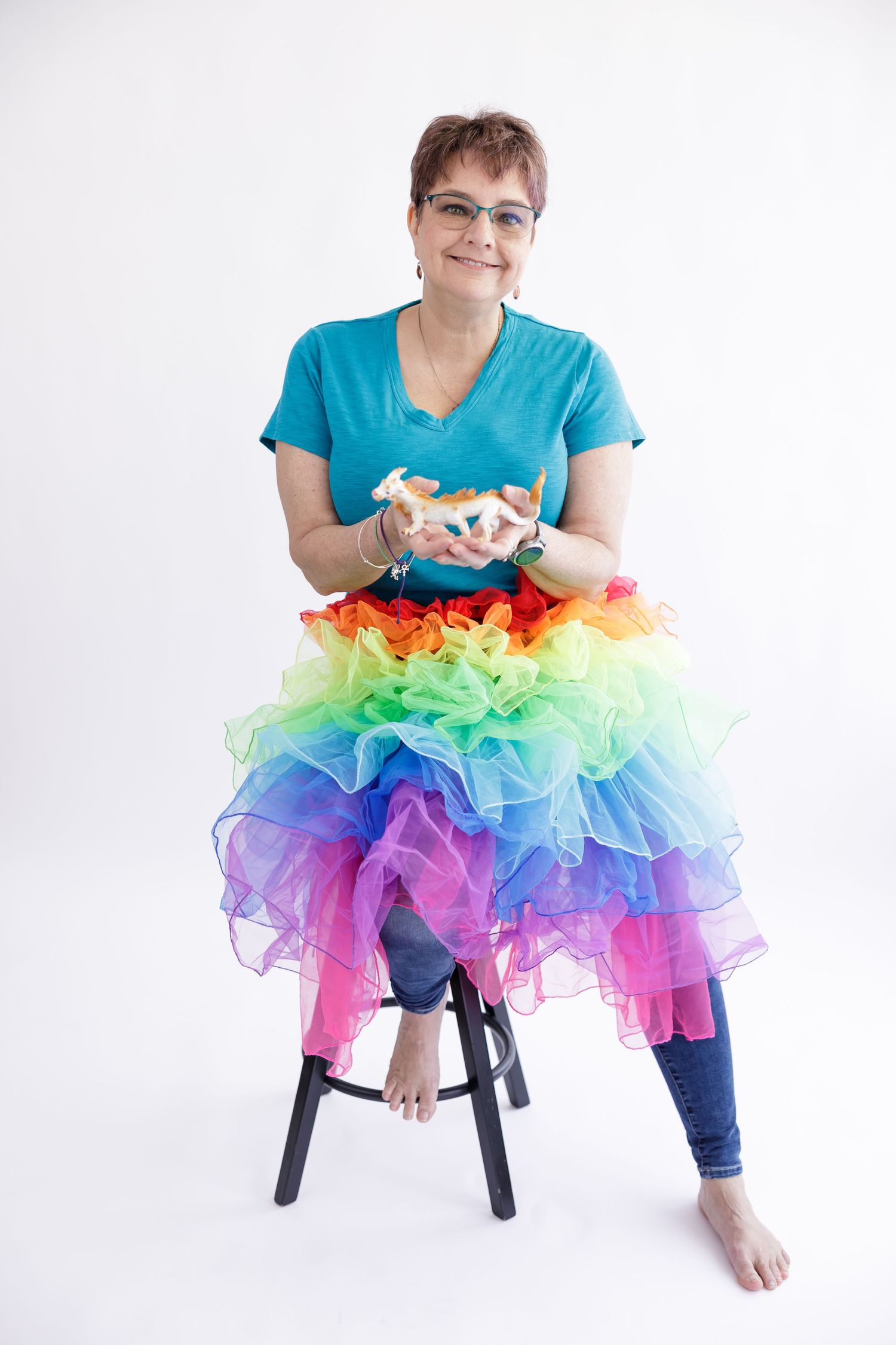 woman business owner coach fun headshot wearing rainbow tutu holding dragon statue in bothell, WA