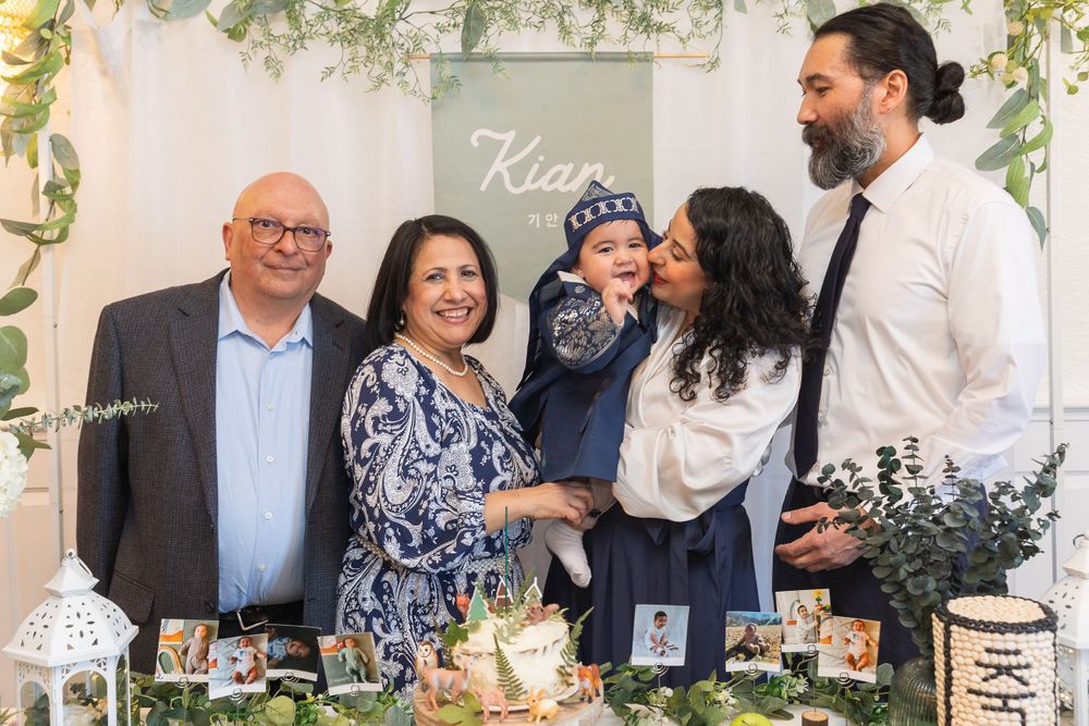 A family gathers around a beautifully decorated dessert table with floral arrangements and treats at a celebration event.