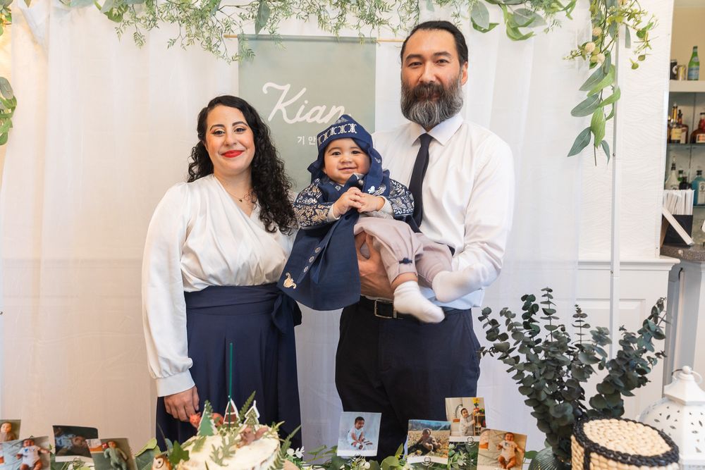 A family poses together at an elegant event with floral decor and a white backdrop.