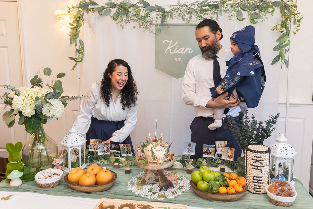 A styled dessert table features fresh fruits, treats and greenery garland against a white backdrop.