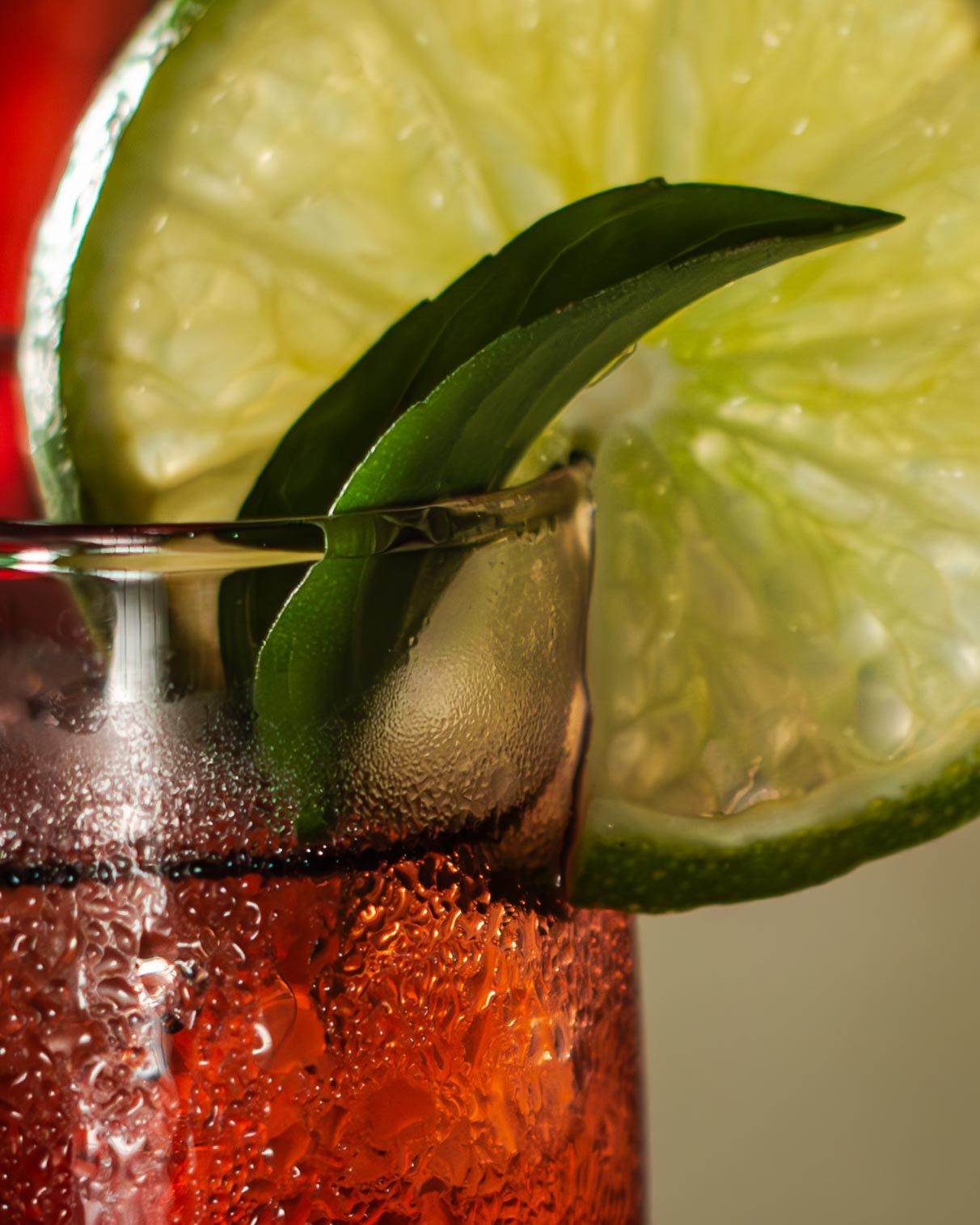 Close-up of a refreshing mocktail garnished with lime slices and basil leaves, capturing the condensation on the glass.