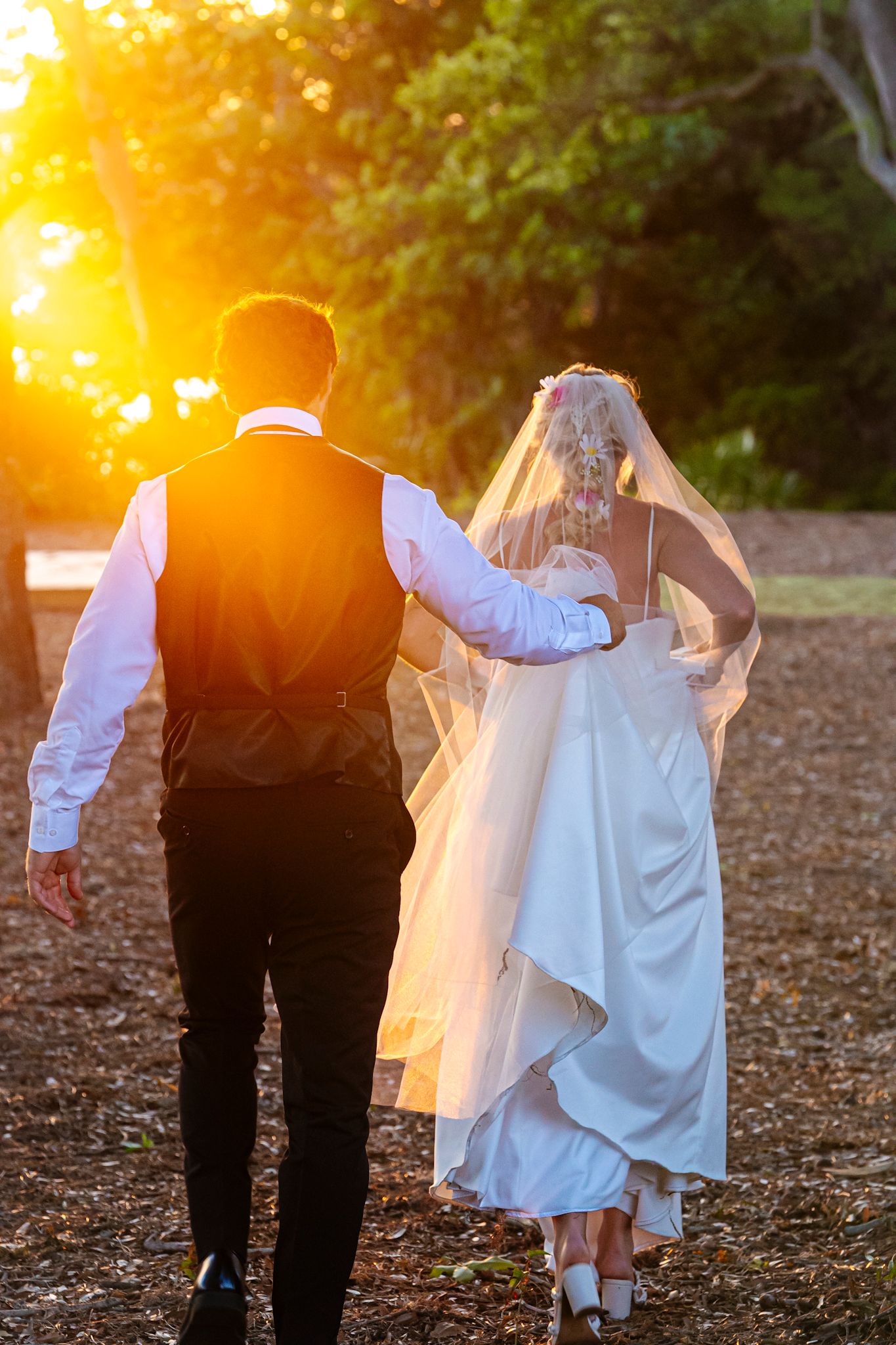 Elegant couple in formal wedding attire pose against urban backdrop.