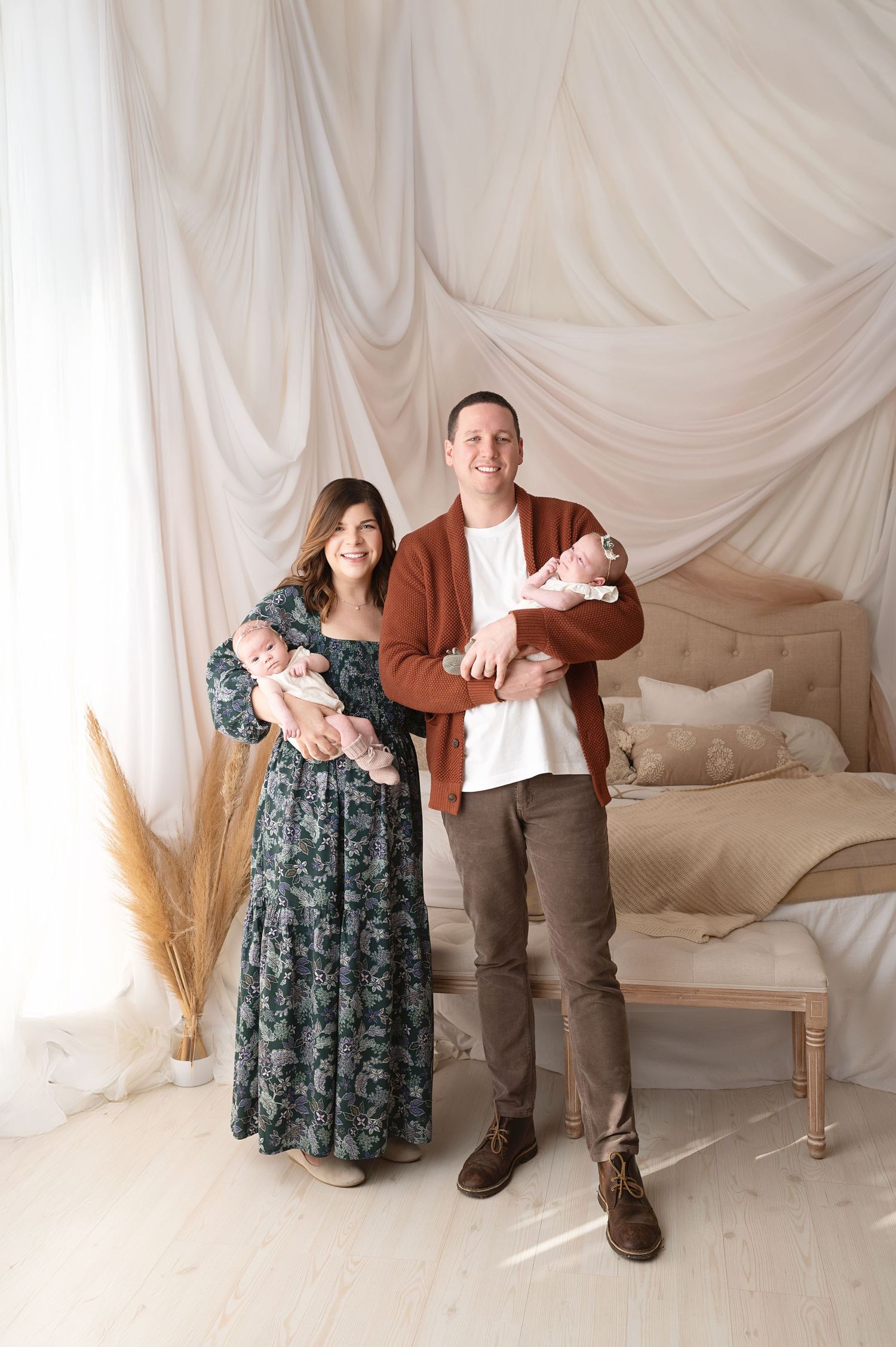 Family portrait session with draped fabric backdrop and pampas grass decor.