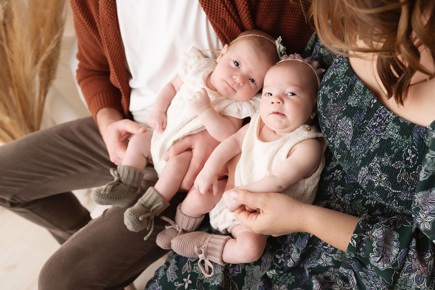 Parents cradling twin newborns in a tender family photoshoot.