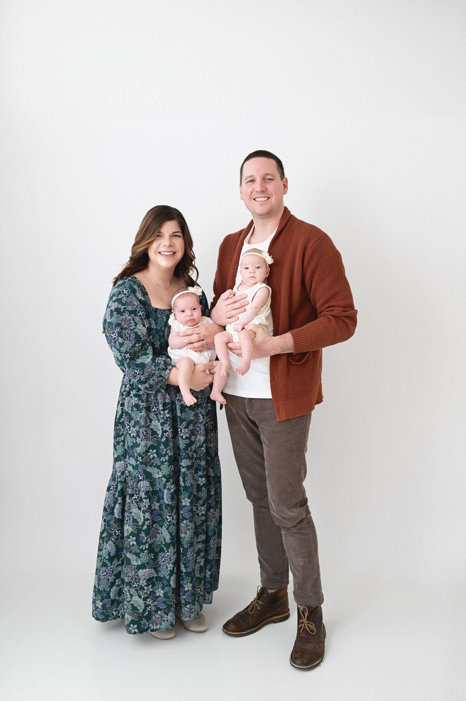 Family portrait session with parents and twin babies against white background.