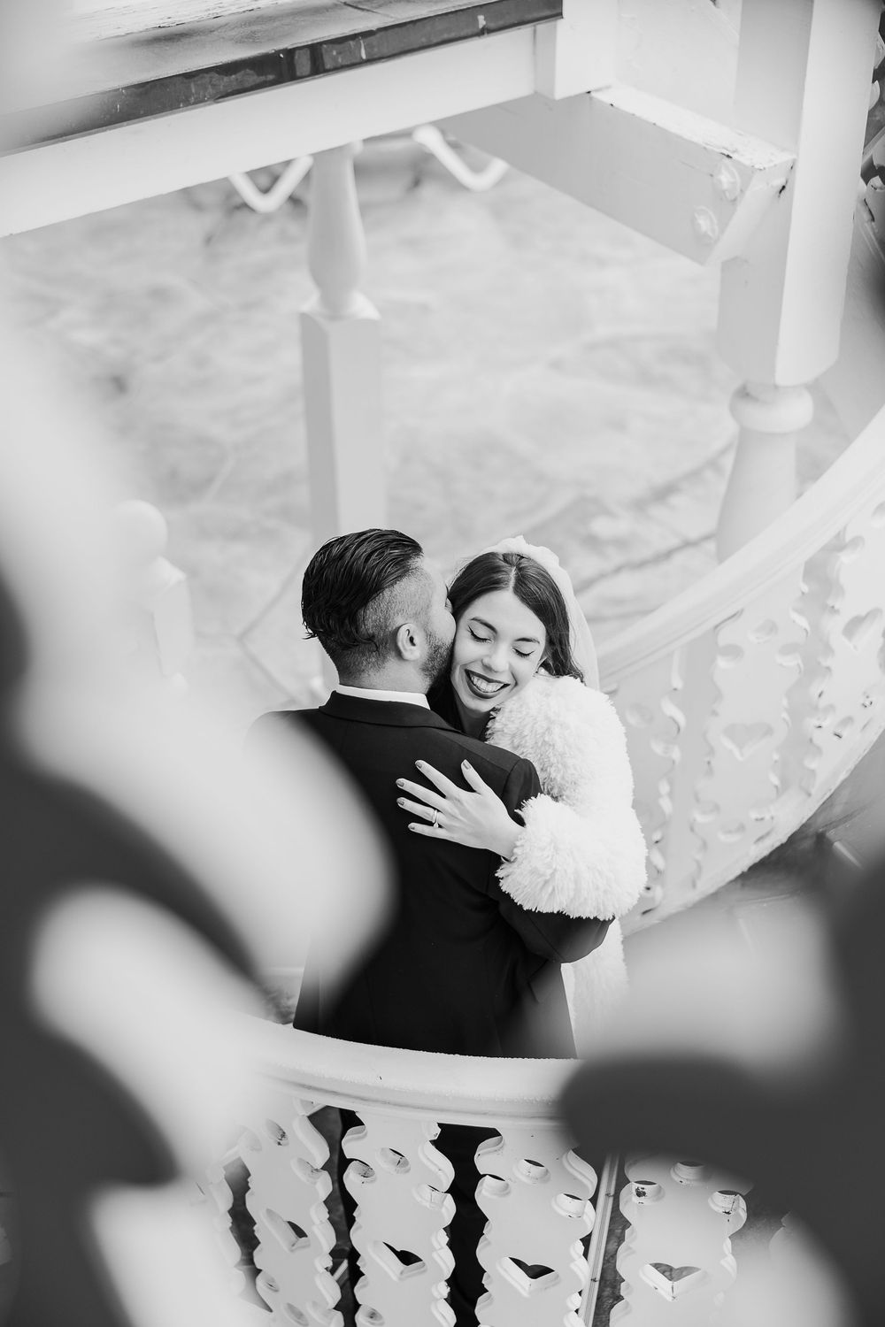 An intimate black and white moment captured of a newlywed couple sharing a joyful embrace.