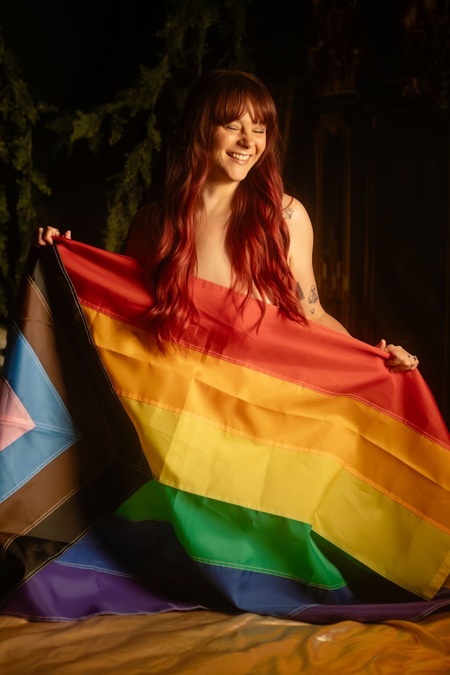 Smiling person holding Progress Pride flag during LGBTQ+ boudoir session at Lock and Key Photography in Fort Worth, TX.