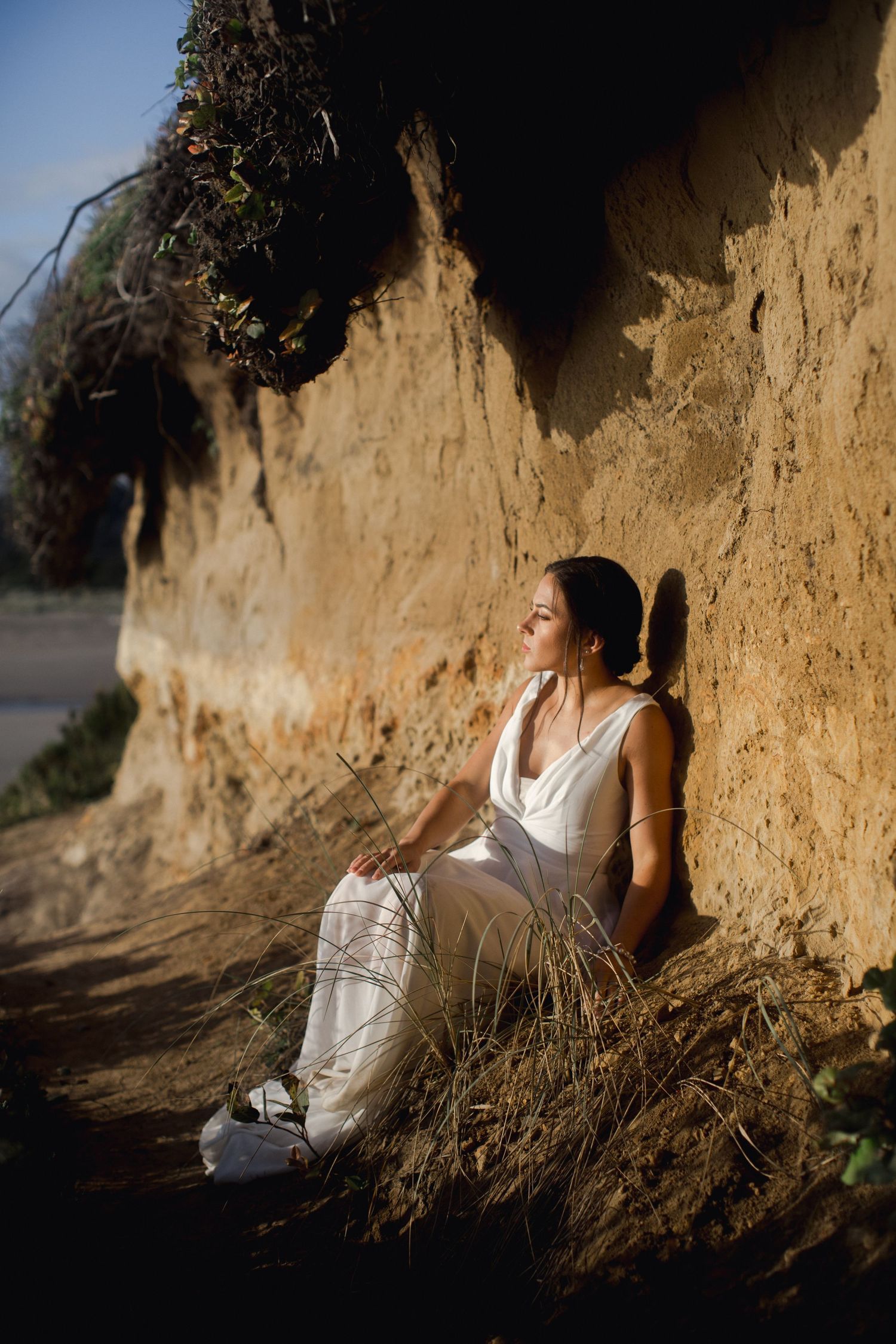 An artistic series of silhouetted portraits against a sunlit sand cliff wall.