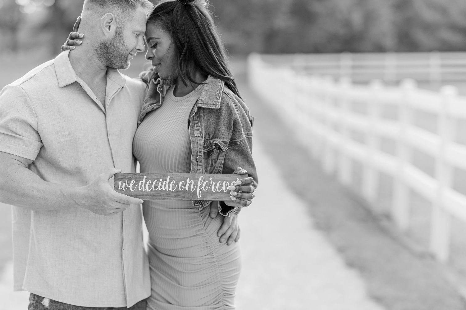 A romantic black and white photograph of a couple embracing outdoors in an intimate moment.