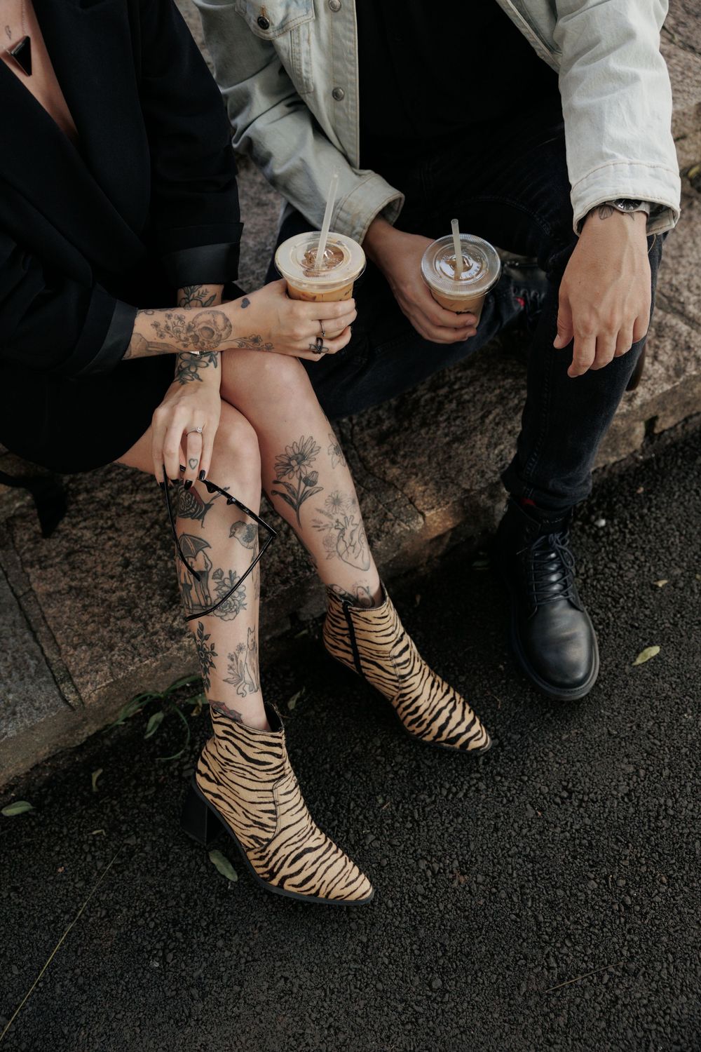 Tattooed legs in tiger print high heels shown in a series of close-up shots on dark ground.