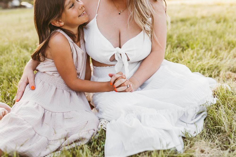 A tender moment between family members sitting together on grass during golden hour.