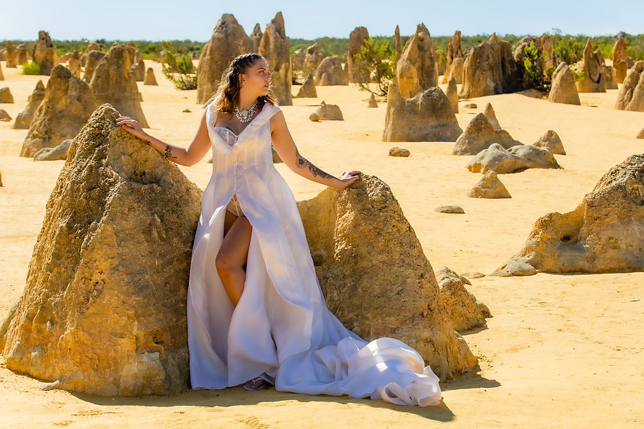 A tourist in white dress exploring the rugged limestone formations at Pinnacles Desert in Western Australia.