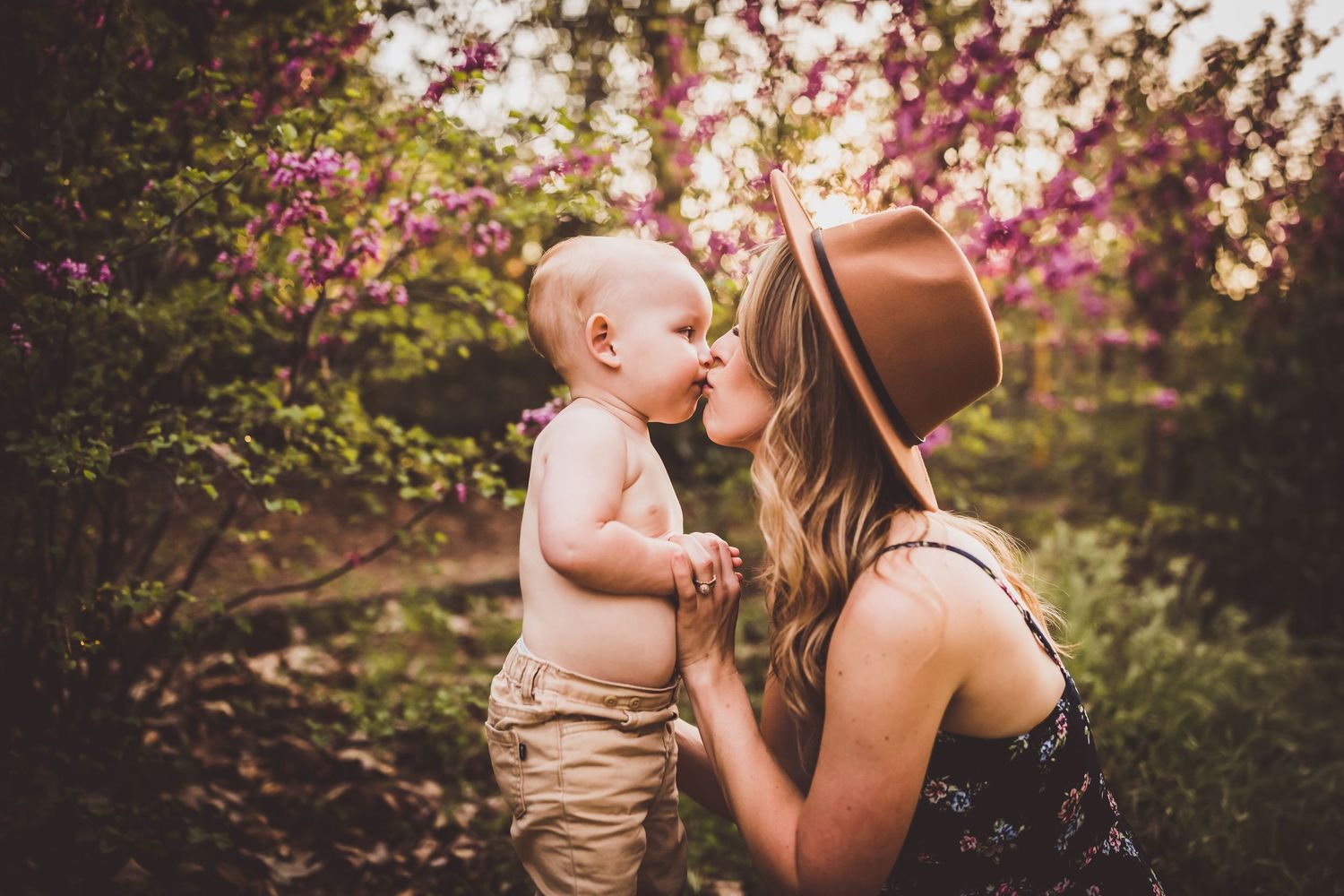 A loving embrace between parent and child in a spring garden with pink blossoming trees in the background.