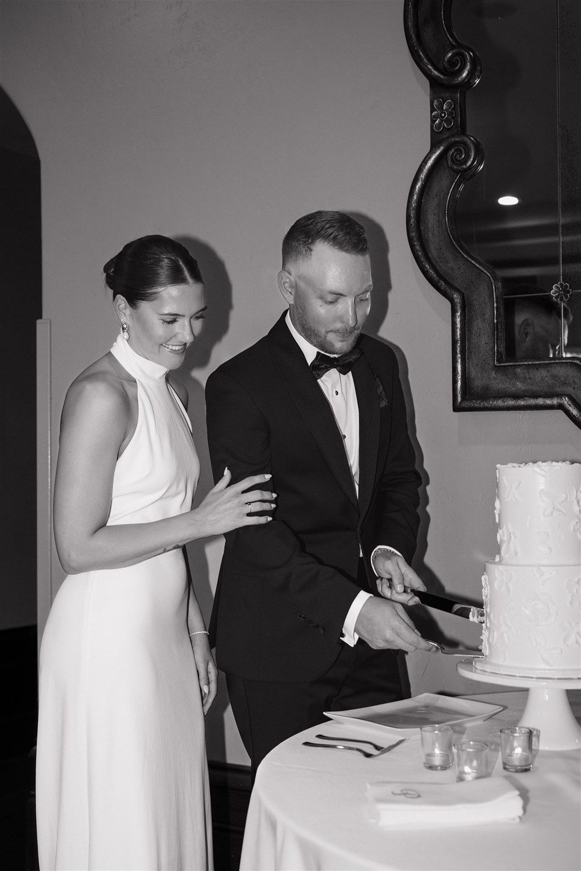 A couple cuts into their tiered white wedding cake in a multi-frame image sequence.