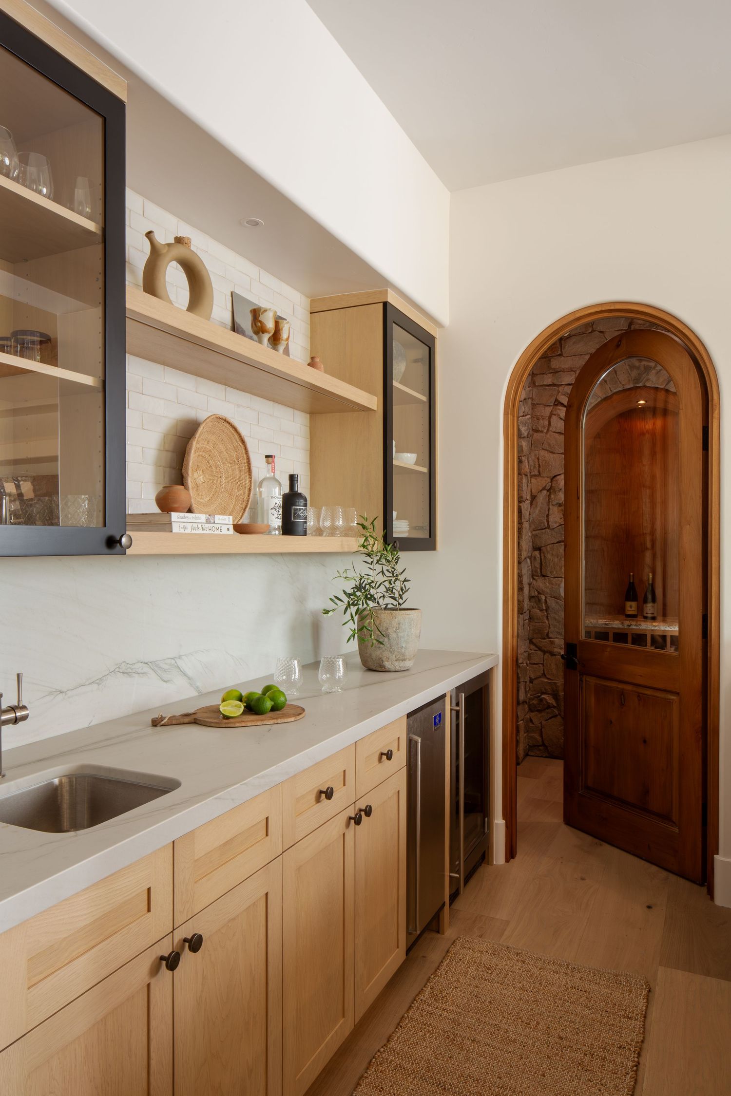 Modern white kitchen with stainless steel stove, decorative wallpaper, table lamp, and cooking utensils in warm natural lighting.