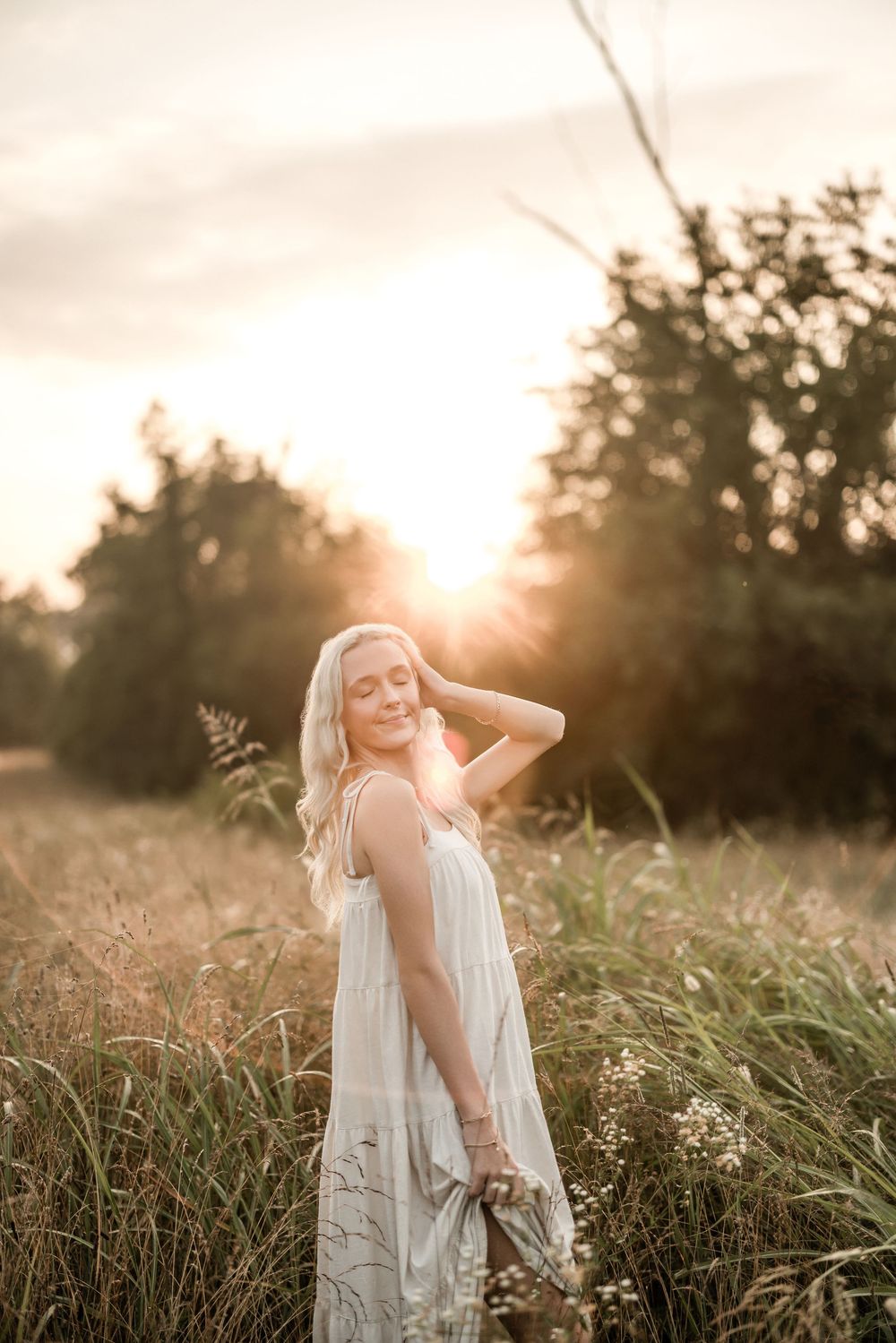 Ethereal sunset photography in tall grass with sunburst through trees.