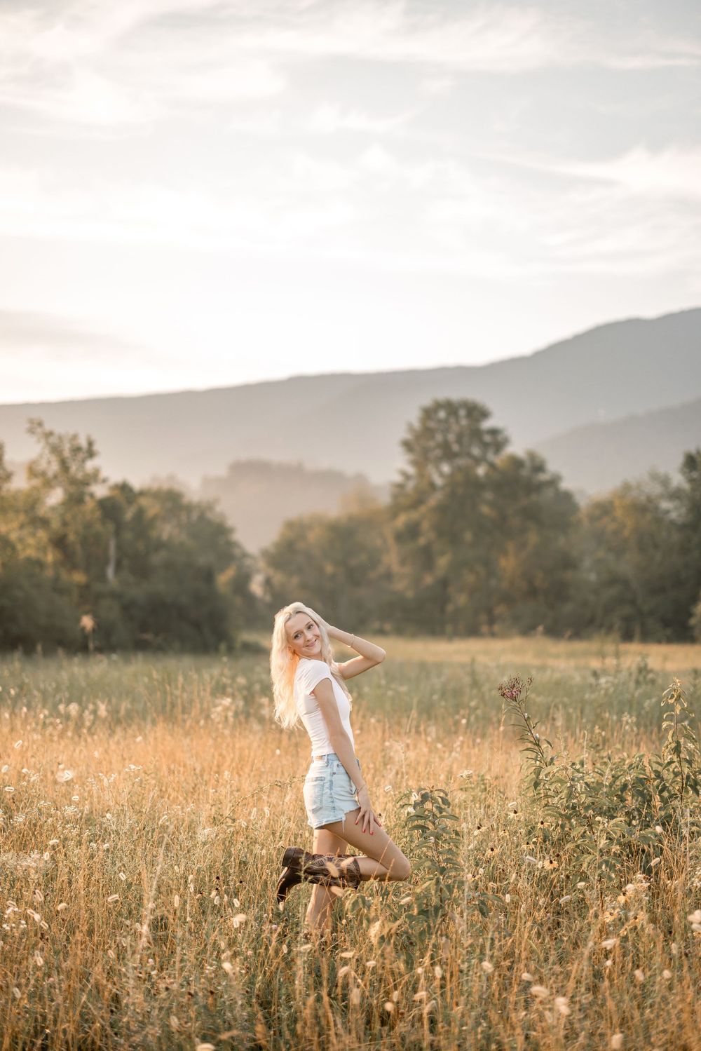 A person in summer attire twirls joyfully in a sun-drenched mountain meadow at golden hour.
