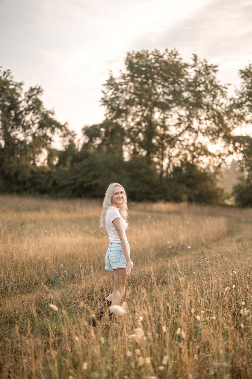 Summer evening portrait in field with mountains and setting sun.