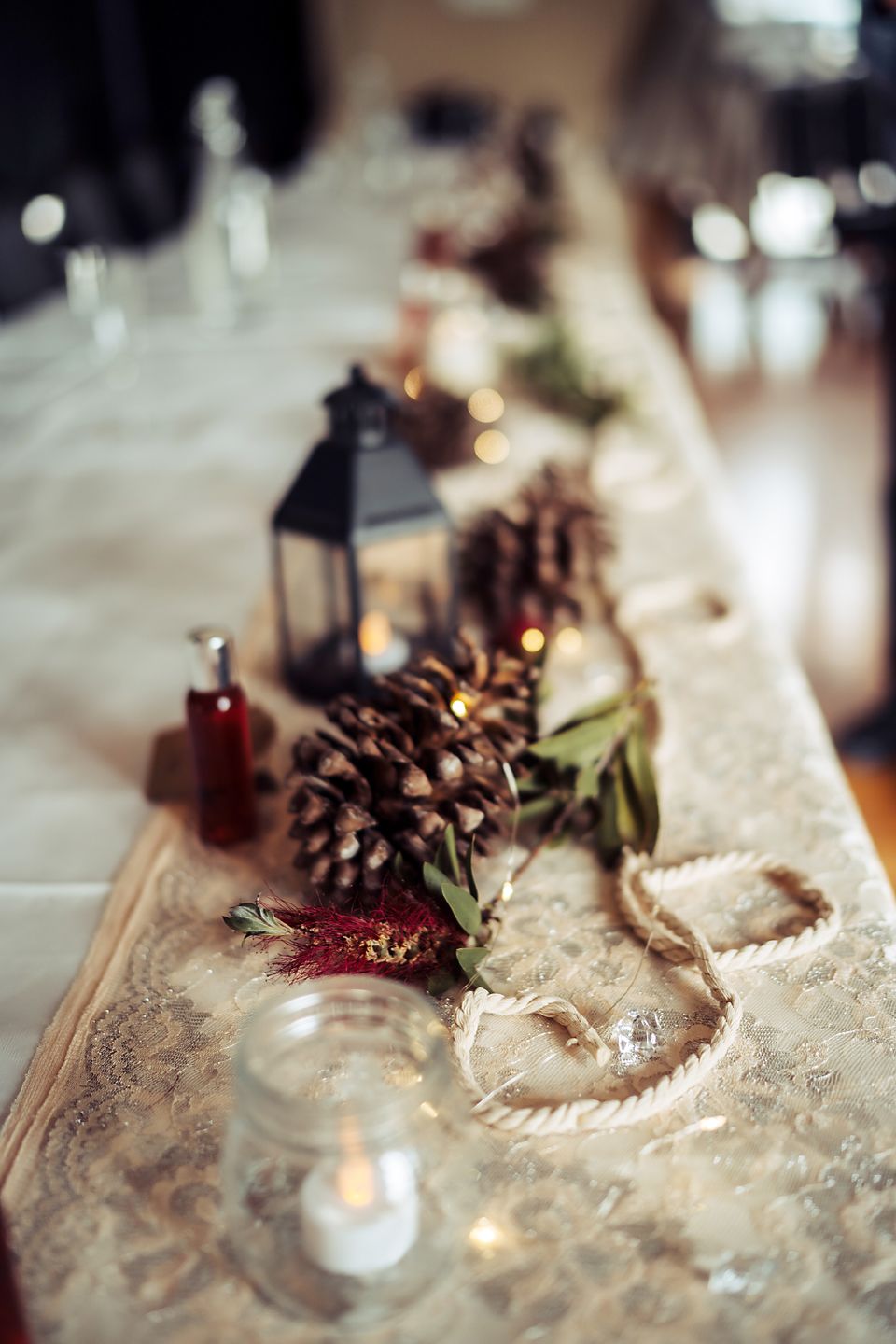 Rustic winter holiday table decor with pinecones and dried red berries on textured white linen.