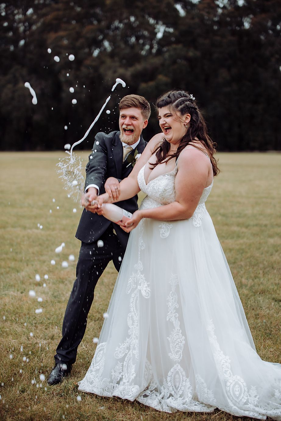 A joyful sequence of a wedding couple popping champagne and celebrating together in an outdoor field.