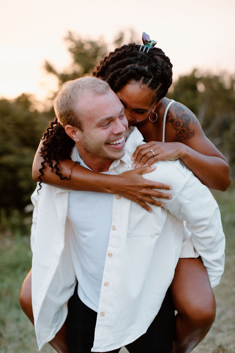 A playful outdoor photoshoot of a couple in white clothing laughing together.