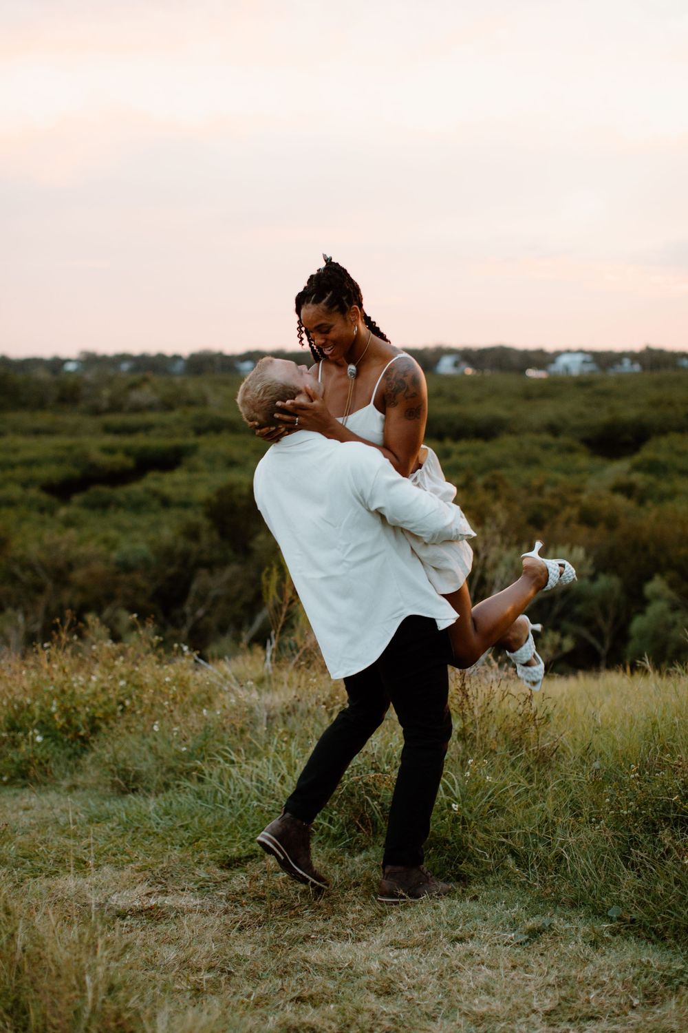 A couple shares a dramatic dip pose in a field during golden hour.