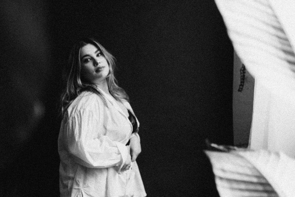 A sequence of five alluring black and white fashion portraits showing different moody poses against a dark background.