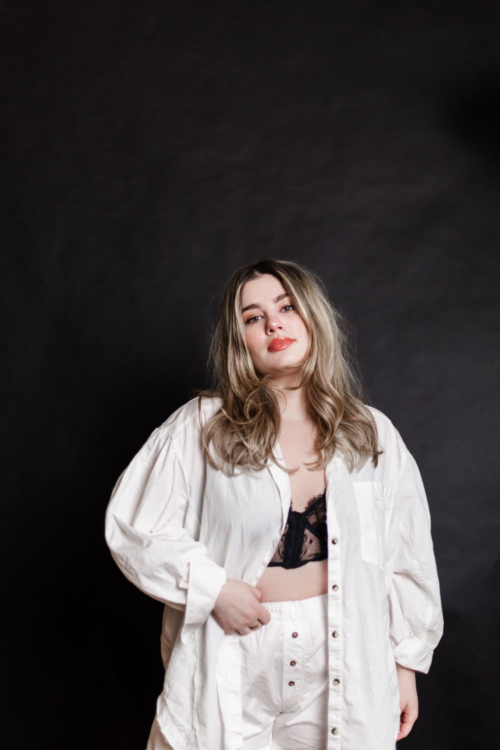 Artistic fashion portrait against dark background featuring a white button-up blouse with dramatic puff sleeves.