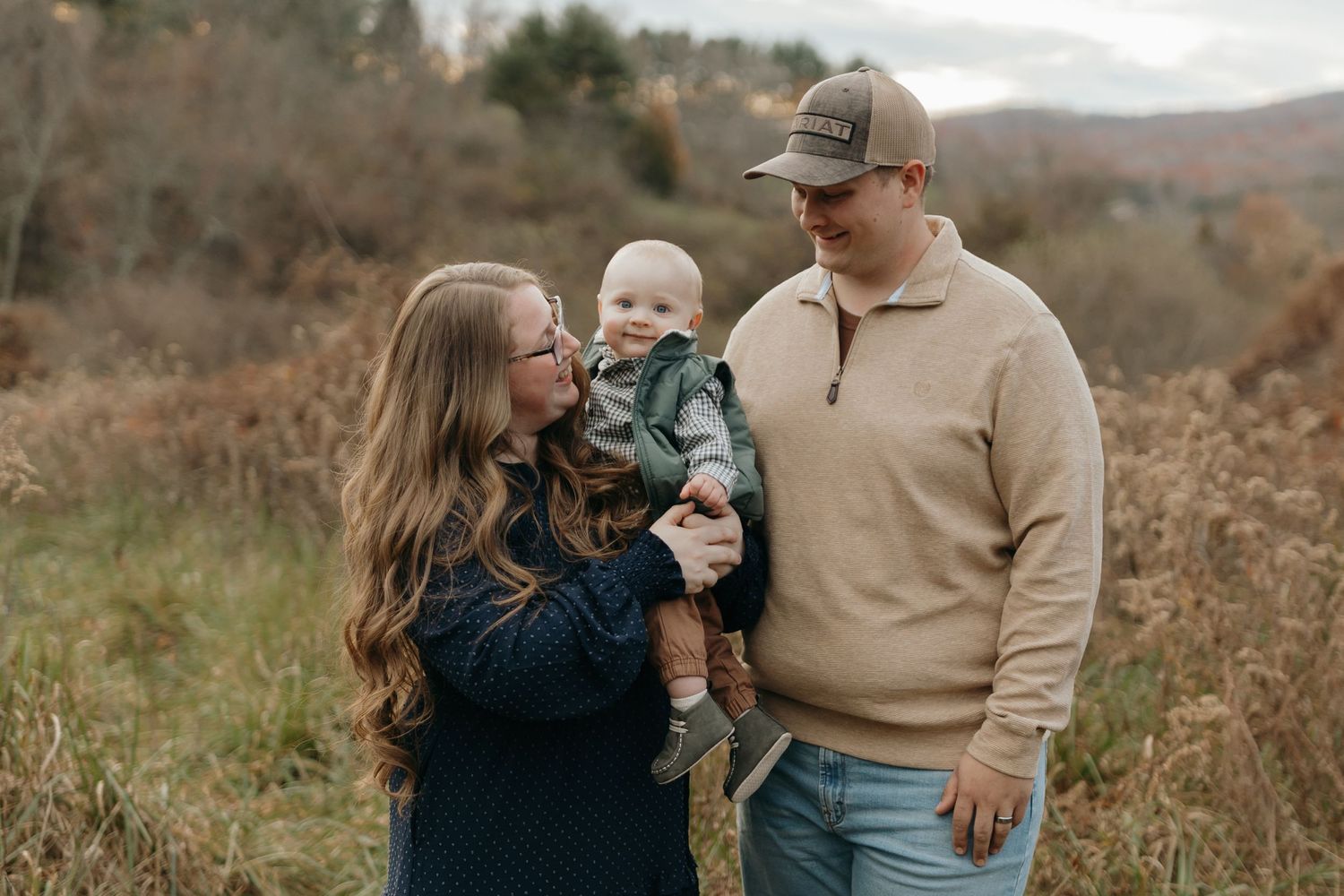 Family portrait taken in rural setting with mountains and autumn foliage in background.