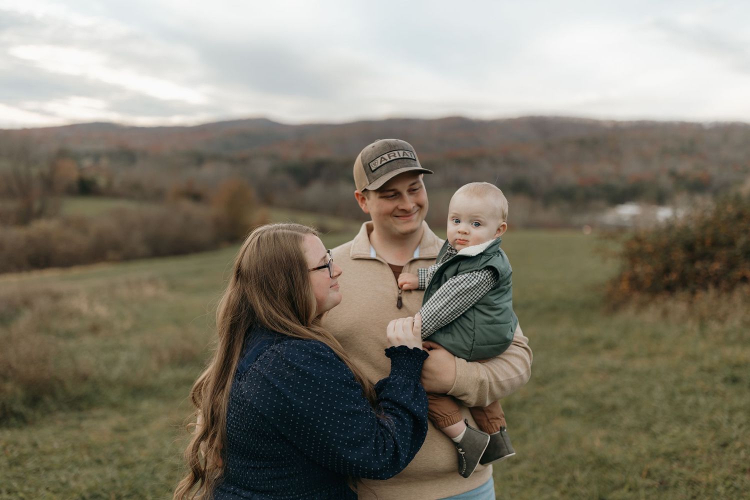 Family sharing intimate moment in outdoor setting with mountain landscape behind them.