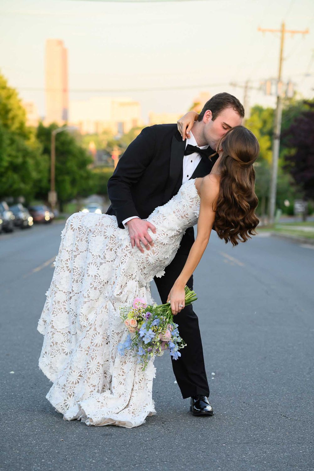 A romantic dip pose between newlyweds on an asphalt road at sunset in a series of progressive shots.