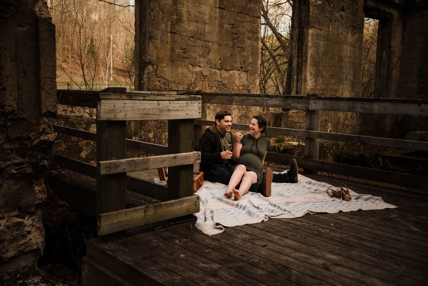 Romantic moment on wooden platform with stone wall backdrop at golden hour.