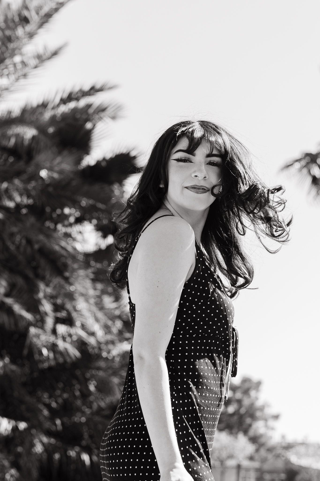 Dramatic black and white profile shot with palm trees in silhouette.