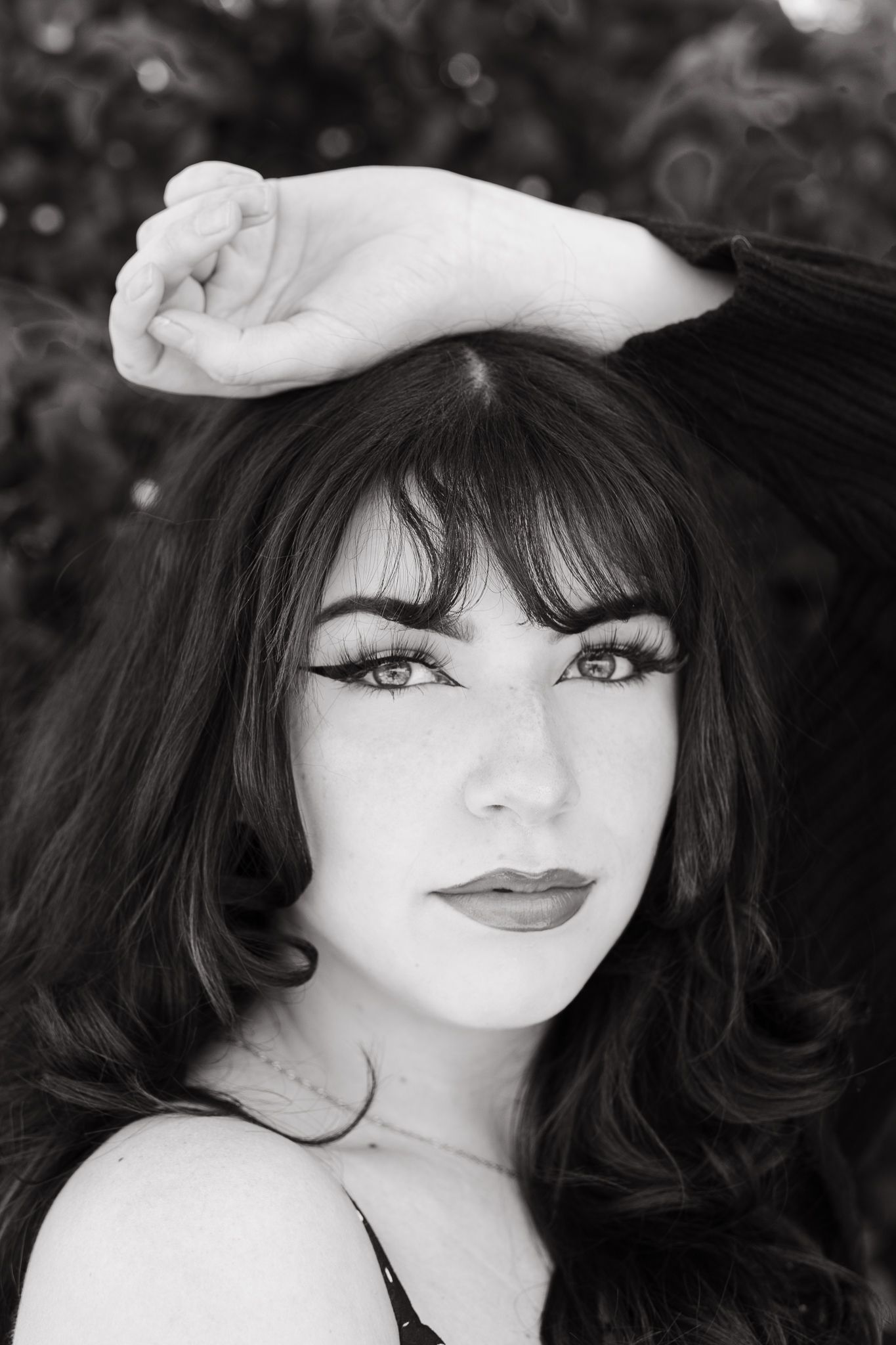 Dramatic black and white portrait with hand posed on head and classic makeup.
