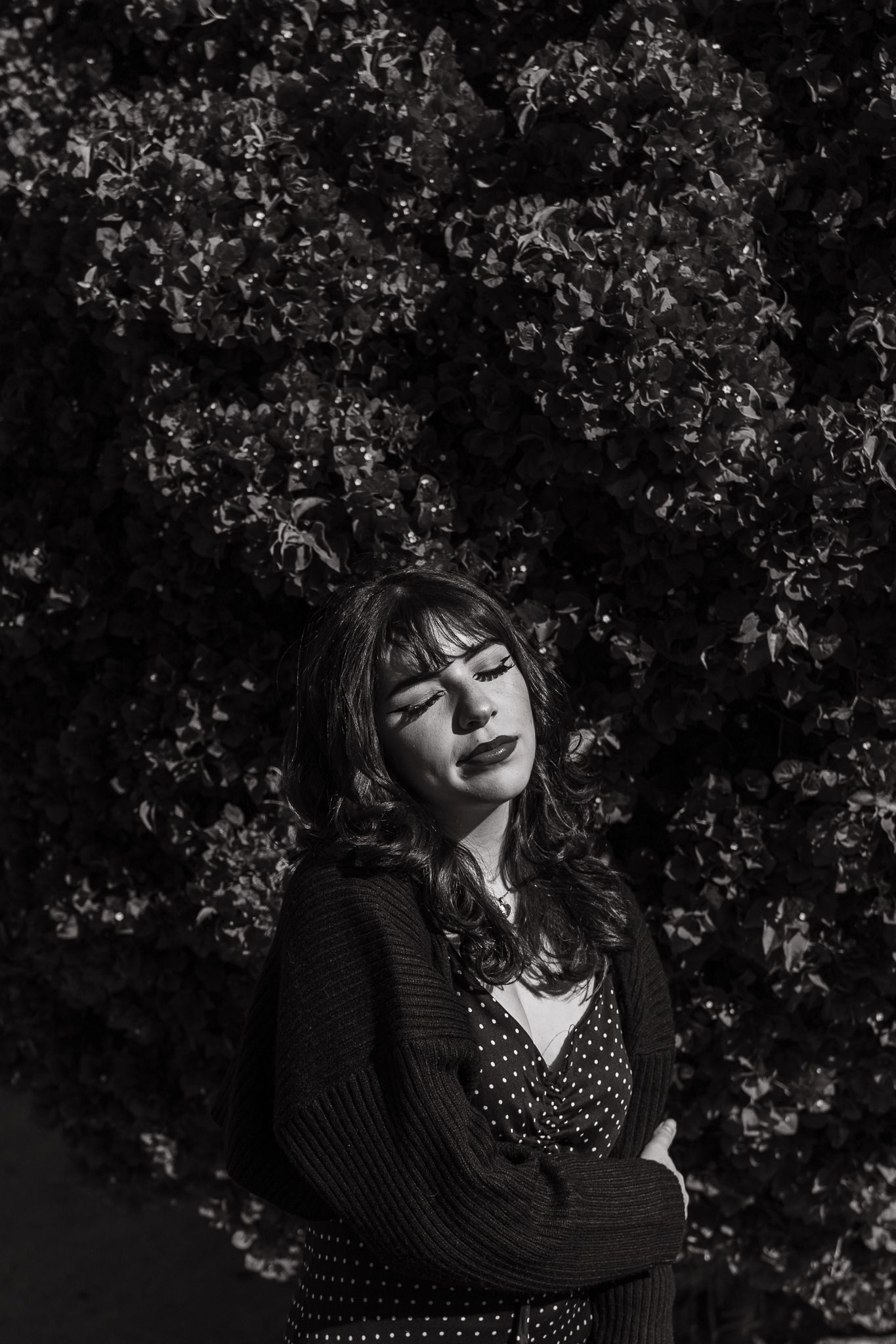 Artistic black and white portrait with natural lighting and crossed arms.