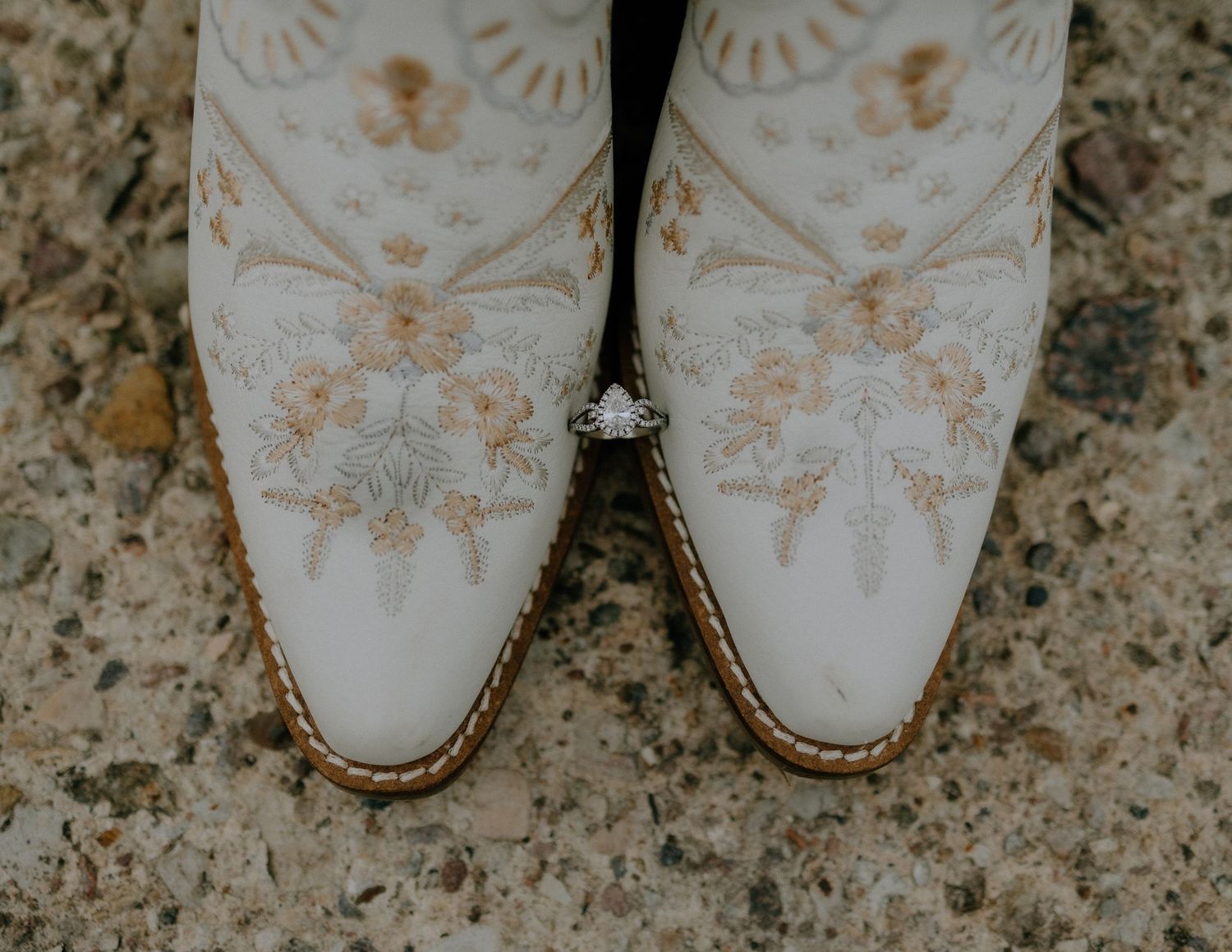 Elegant white cowboy boots with intricate gold embroidered floral designs on leather.