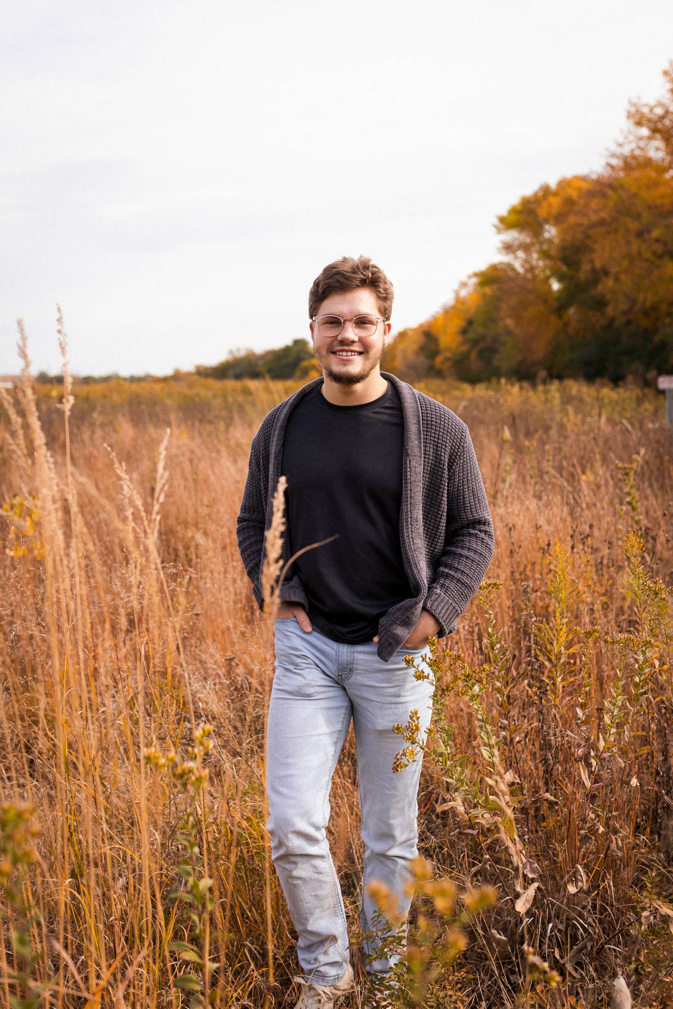 Male senior walking toward camera smiling. Captured at Sauk River Regional Park by Shania Hirdler Photography.