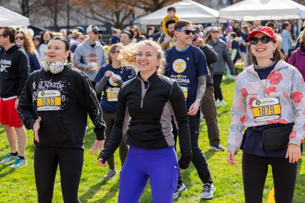 Group of energetic participants gathering before a charity race event on grass field.