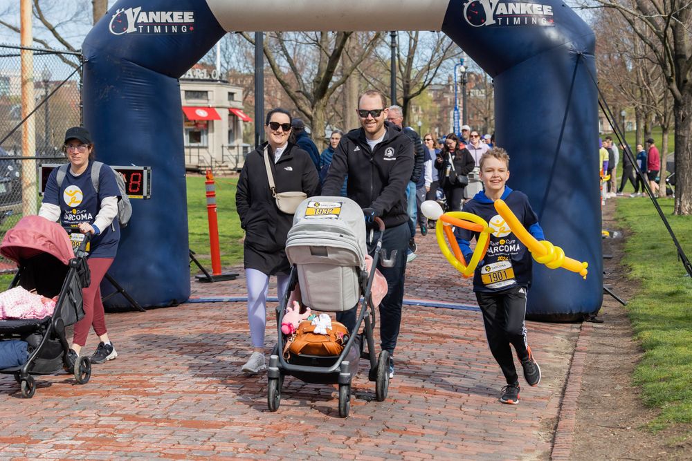 Participants crossing finish line under blue inflatable arch during community race.