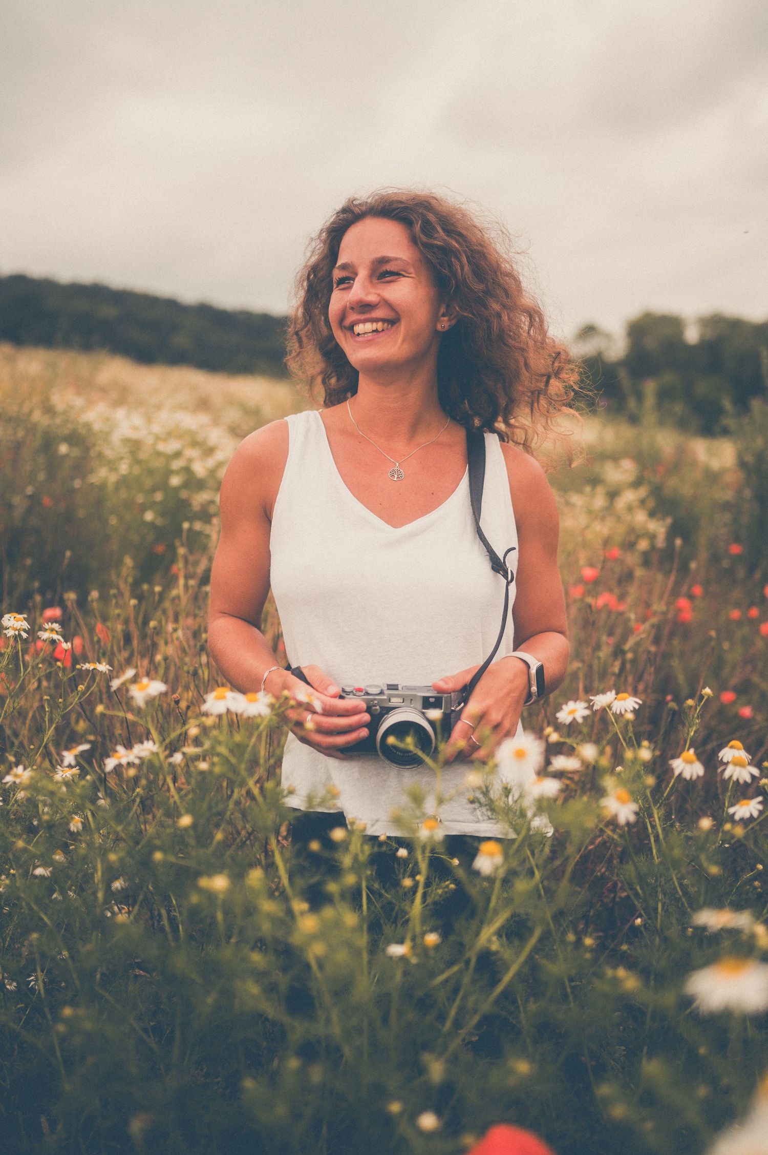 Person holding vintage camera in a wildflower meadow on a summer day.