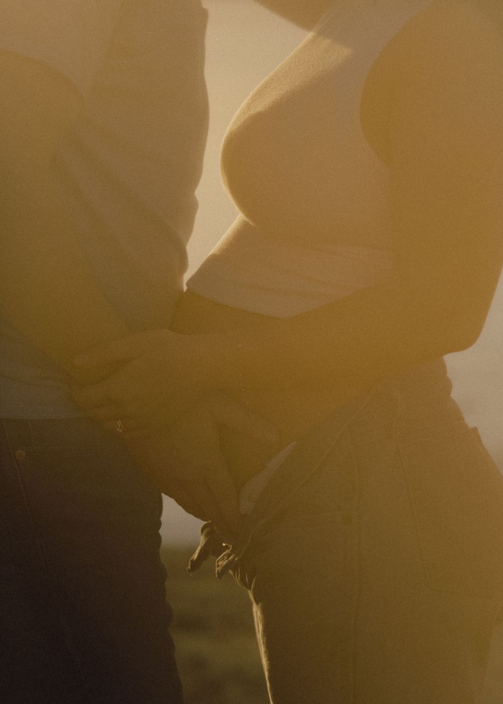 Silhouetted figures embracing in romantic golden light with soft shadows and warm tones.