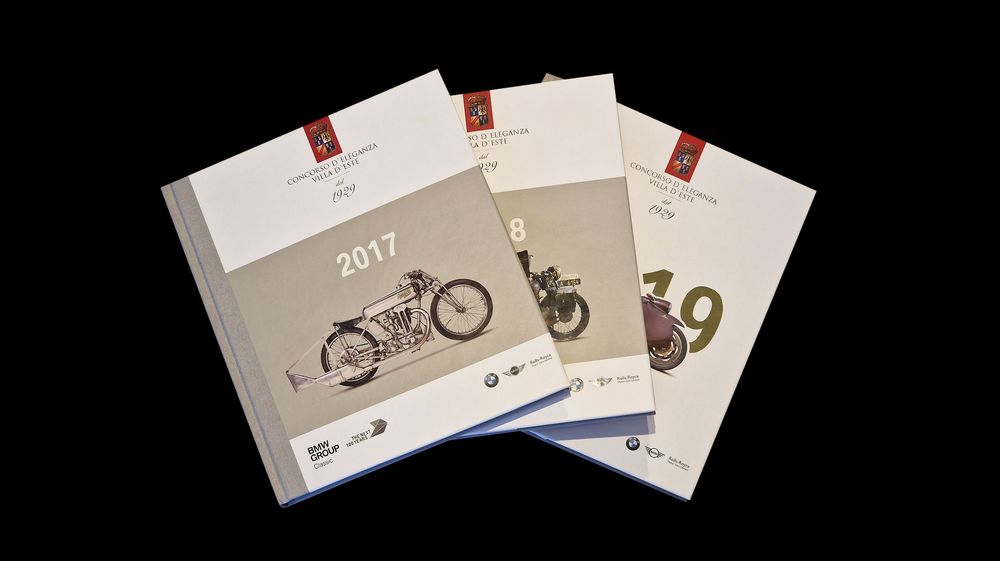 Three white calendar or catalog covers featuring vintage motorcycle illustrations arranged on a dark background.