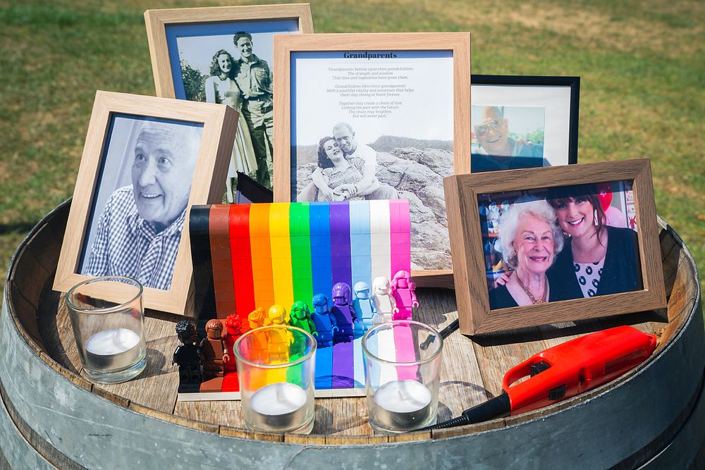 A collection of framed photographs and a rainbow ribbon display arranged on a rustic wooden barrel.